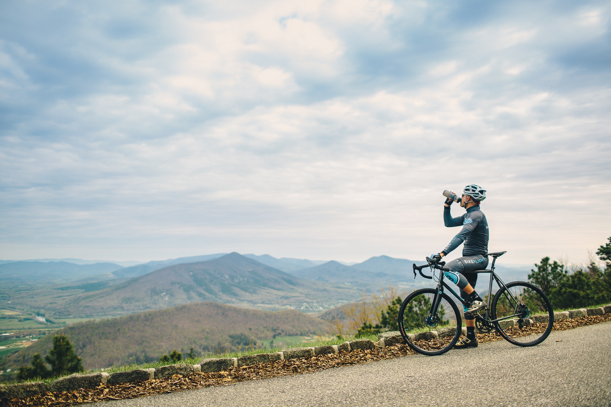 Cycliste qui s'arrête au bord de la route pour admirer la vue sur les montagnes.